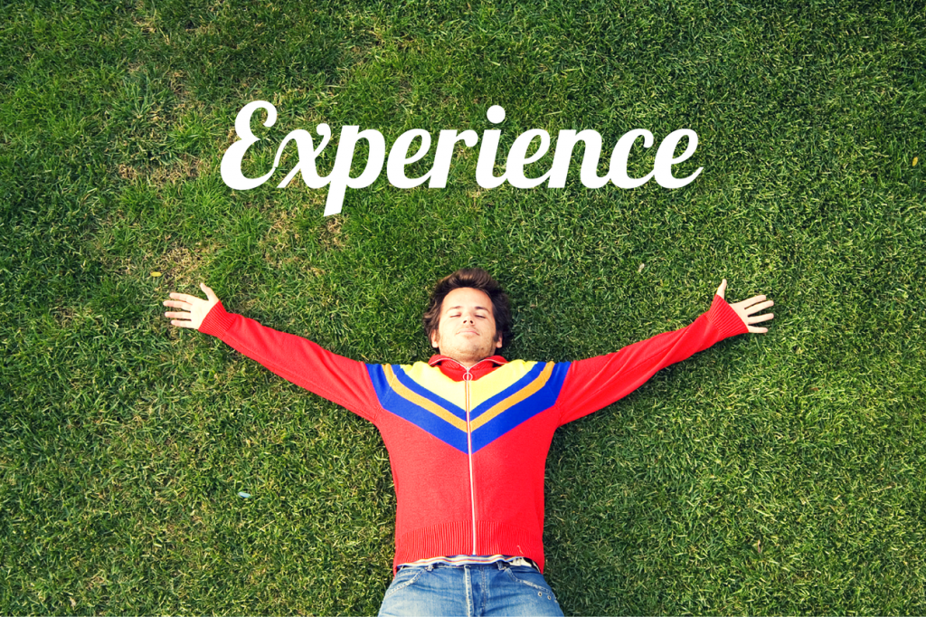 Man lying happily on the grass and the word "Experience"