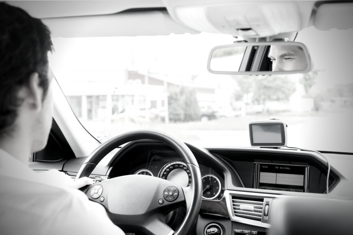 Photo of man driving car taken from back seat