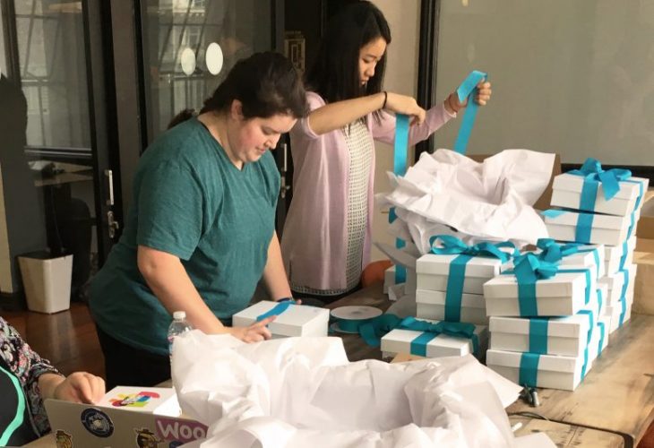 Kelly and Lauren tying ribbons on gift boxes