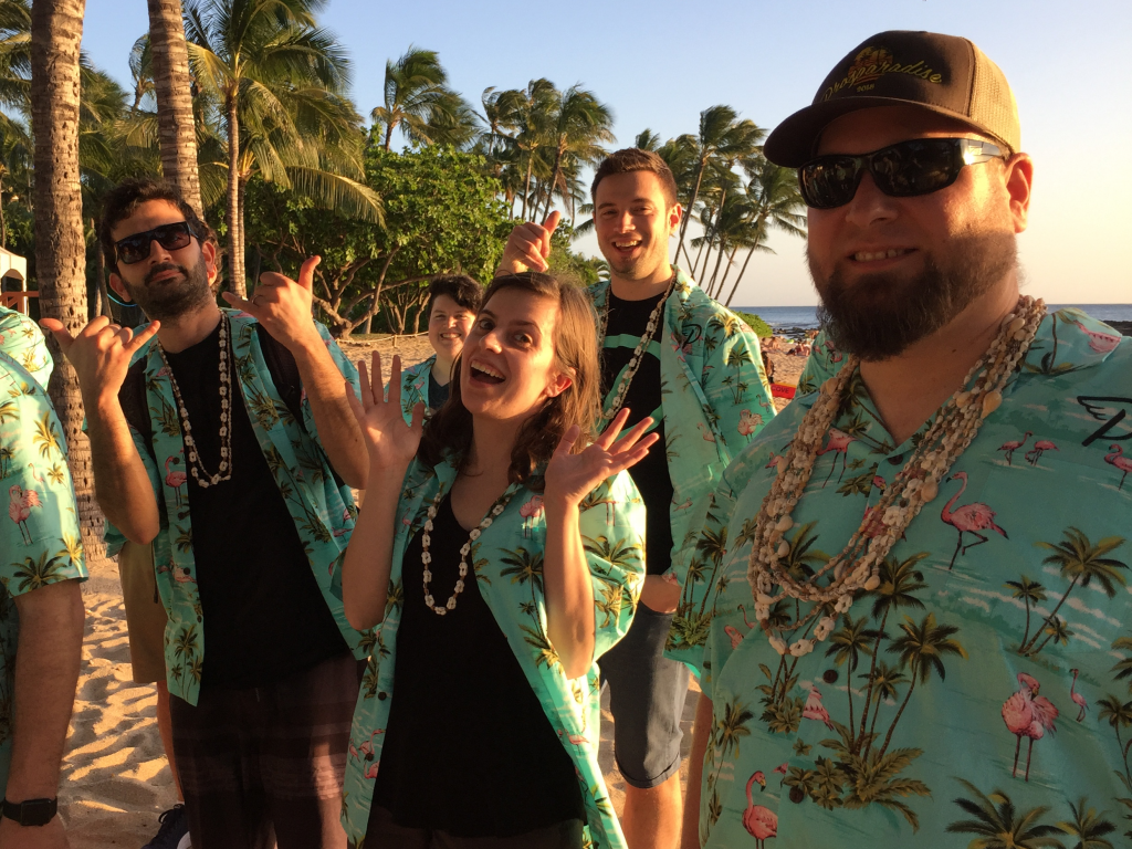 Four people smiling and goofing around at the beach